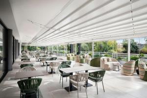 a restaurant with tables and chairs and windows at Courtyard by Marriott Rome Central Park in Rome