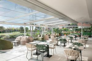 a restaurant with tables and chairs and windows at Courtyard by Marriott Rome Central Park in Rome