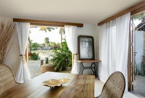 a dining room with a wooden table and a mirror at Villa Praia - La Villa Group in Jericoacoara