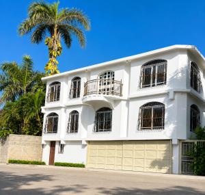 a white building with a palm tree in the background at Los Patos Waterfront Private Suites in Los Patos