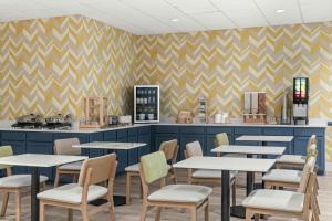 a restaurant with tables and chairs in front of a counter at City Express By Marriott Findlay in Findlay