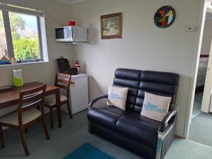 a living room with a leather couch and a table at Digs Homestay in Stratford
