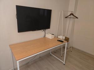 a desk with a flat screen tv on a wall at 지슬스테이 in Pyoseon