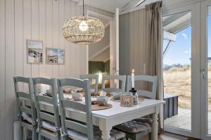 a dining room with a table with chairs and a chandelier at 440-Hvide-Sande-Strandkrogvejen-60 in Hvide Sande