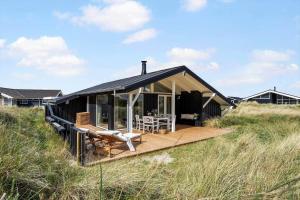 a house with a wooden deck in the middle of a field at 440-Hvide-Sande-Strandkrogvejen-60 in Hvide Sande