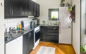a kitchen with black cabinets and a white refrigerator at Nice Apartment In Rysstad With Wifi in Rysstad