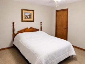 a bedroom with a white bed and a wooden door at Kaw Drive Guest House in Olathe