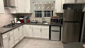 a kitchen with white cabinets and a stainless steel refrigerator at Journey House LA in Los Angeles