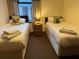 two beds in a room with towels on them at Burnside Holiday Cottage 2 in Fochabers