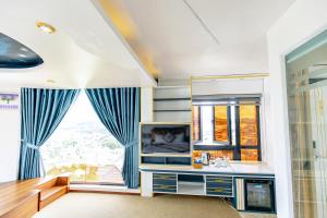 a living room with a tv and a window at Dallas Hotel Dalat in Da Lat