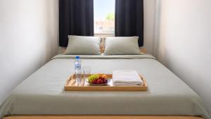a tray with a bottle of water and a bowl of fruit on a bed at Élégant stays in Vilvoorde