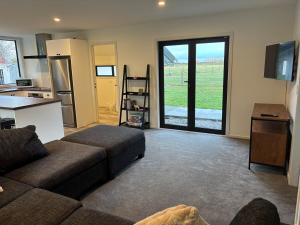 a living room with a couch and a kitchen at Cottage Lifestyle in Fernside +23 photos