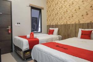 a bedroom with two beds with red and white sheets at RedDoorz @ Bukit Dieng 2 in Malang