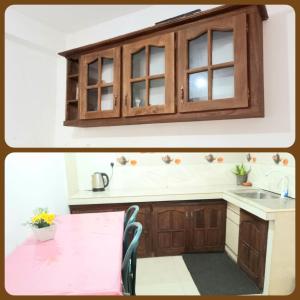 a kitchen with wooden cabinets and a pink table at City Lavish in Nuwara Eliya