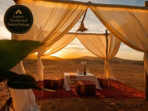 a tent with a table in the middle of the desert at Luxury Traditional Sahara Package in Merzouga +31 photos