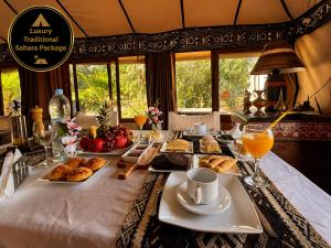 a table with breakfast foods and orange juice on it at Luxury Traditional Sahara Package in Merzouga