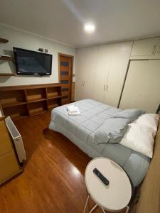 a bedroom with a bed and a table and a tv at Hotel Peregrino Suites in Concepción