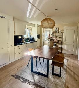 a large kitchen with a wooden table and chairs at Vakantiewoning De Bosrand Aan Zee in Sint Annaland