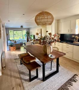 a kitchen and living room with a table with a vase of flowers at Vakantiewoning De Bosrand Aan Zee in Sint Annaland