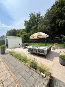 a patio with a table and an umbrella and benches at Vakantiewoning De Bosrand Aan Zee in Sint Annaland