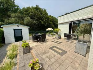 a patio with a table and chairs and a building at Vakantiewoning De Bosrand Aan Zee in Sint Annaland