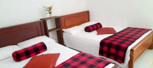 two beds with red and black plaid sheets in a room at City Lavish in Nuwara Eliya