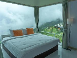 a bedroom with a bed in front of a large window at ม่อนทับเบิก รีสอร์ท ภูทับเบิก in Ban Maeo Thap Boek