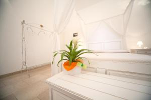 マリーナ・ディ・ペスコルーゼにあるAntica Masseria Ficazzana - Tenutaの白いベッドとテーブルの上に植物が備わるベッドルーム1室が備わります。