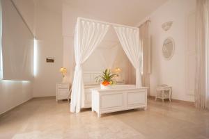 a white room with a bed with a plant on it at Antica Masseria Ficazzana - Tenuta in Marina di Pescoluse