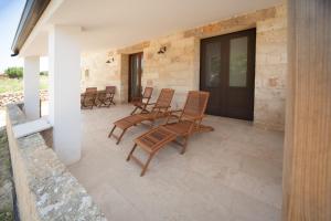 a patio with rocking chairs and a black door at Antica Masseria Ficazzana - Tenuta in Marina di Pescoluse