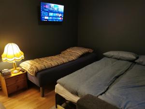 a bedroom with two beds and a tv on the wall at Siva's Apartment in Svolvær