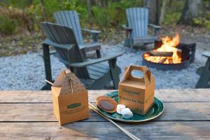 a table with a plate of food next to a fire at Postcard Cabins Mount Adams, Outdoor Collection by Marriott Bonvoy in Glenwood
