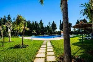 a garden with a swimming pool and a palm tree at Cozy Studio Near Beach with Pool Access in Martil +22 photos