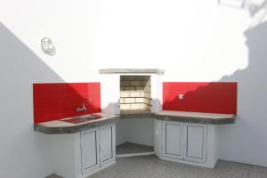 una cucina con lavandino e parete rossa di Cantinho Das Praias a Vila Franca do Campo Altre 59 foto