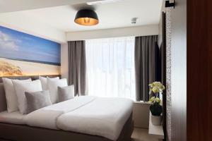 a bedroom with a large white bed and a window at TRYP Badhotel The Hague Scheveningen BRAND NEW in Scheveningen