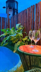 two wine glasses sitting on a table next to a fence at Flat em Carapibus moderno e aconchegante in Conde