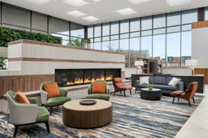 a lobby with a fireplace and chairs and a table at Indianapolis Marriott East in Indianapolis