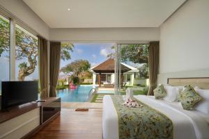 a bedroom with a bed and a tv and a pool at Pandawa Cliff Ocean view with private beach in Nusa Dua