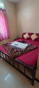a bed with a red bedspread and a laptop on it at Yamuna rooms and dormitory in Ooty