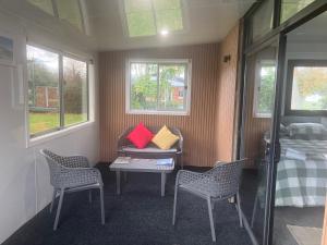 a small room with chairs and a bed and windows at Cameo B&B in Matamata