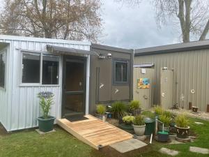 a tiny house with a porch and potted plants at Cameo B&B in Matamata