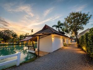a building with a fence next to a body of water at Kenikar Raintree Resort Chumphon in Chumphon