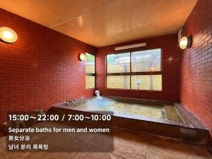 a large bathroom with a hot tub in a brick wall at Kujiranoonaka in Minamitsuru