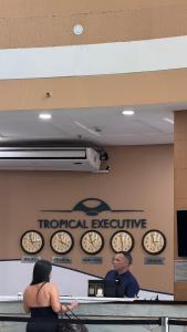 a man and a woman sitting at a table with clocks on the wall at Flat Tropical Hotel Vista Espetacular in Manaus +16 photos