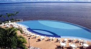 a large swimming pool with chairs and the water at Flat Tropical Hotel Vista Espetacular in Manaus