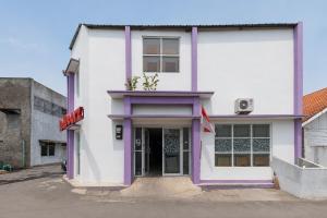 a white building with purple trim on a street at RedDoorz Plus @ Tuparev Cirebon 2 in Cirebon