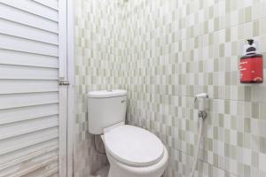 a bathroom with a toilet in a white tiled wall at RedDoorz Plus @ Tuparev Cirebon 2 in Cirebon