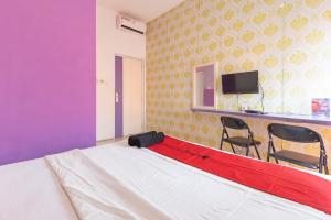 a bed in a room with two chairs and a tv at RedDoorz Plus @ Tuparev Cirebon 2 in Cirebon +18 photos