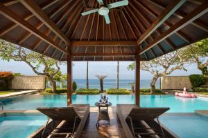 a swimming pool with chairs and a ceiling fan at Pandawa Cliff Ocean view with private beach in Nusa Dua