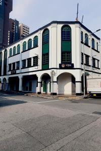 a white building with green windows on a city street at GoStay Pods at Perak Road in Singapore